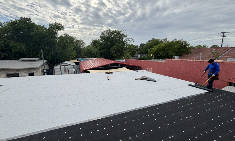 Commercial roof repair professional addressing ponding water on a flat roofing system